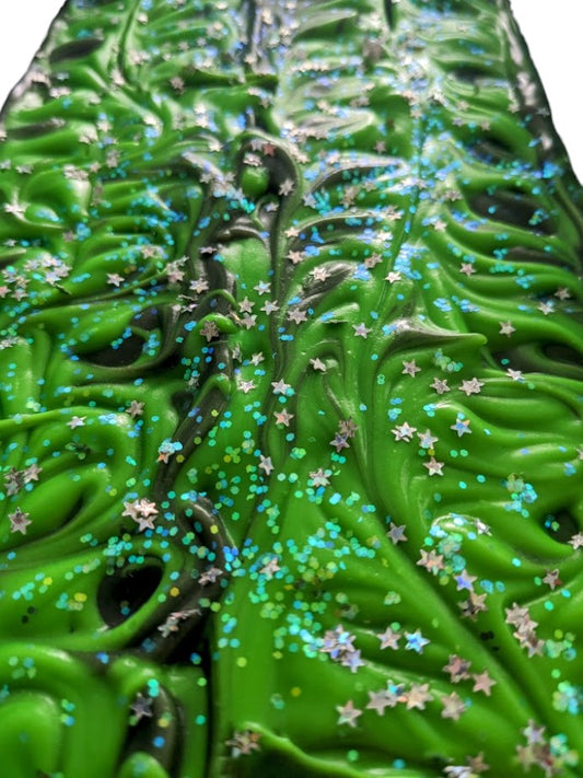 Hemp oil and goat milk soap bar with black background with a dusting of holographic sparkles with delicate neon green swirls dancing throughout the soap body.  Topped with biodegradable star glitter.  Fragranced with Agave Bloom fragrance oil.