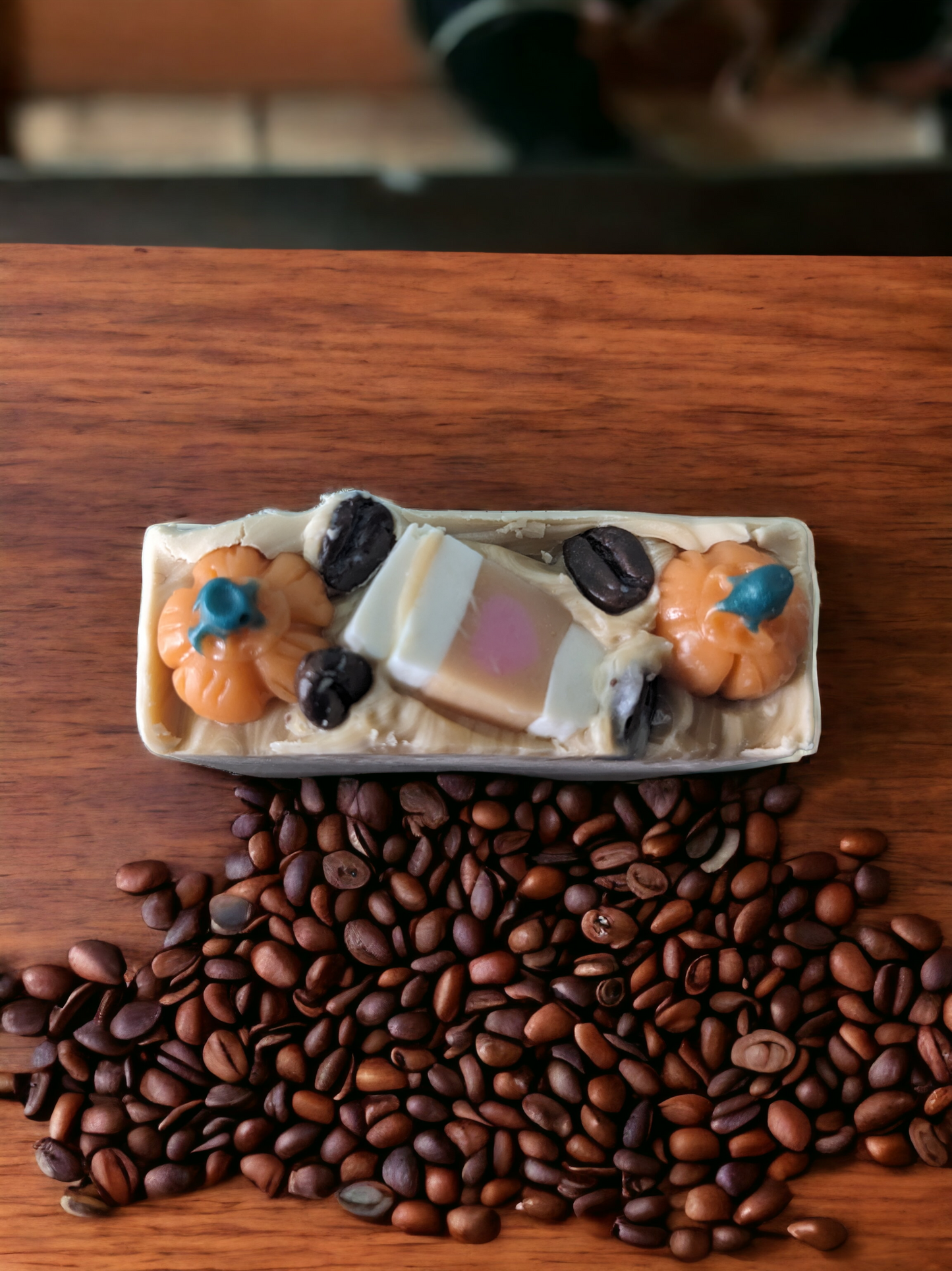 Pumpkin Spice Latte To Go, Luxury Artisan Bar soap . The top of the handcrafted soap bar has a creamy white top that is decorated with delightful pumpkins, a to go coffee cup and coffee beans. The body of the bar of soap has light latte brown with a pumkpin and to go coffee cup that go through the width of the soap.