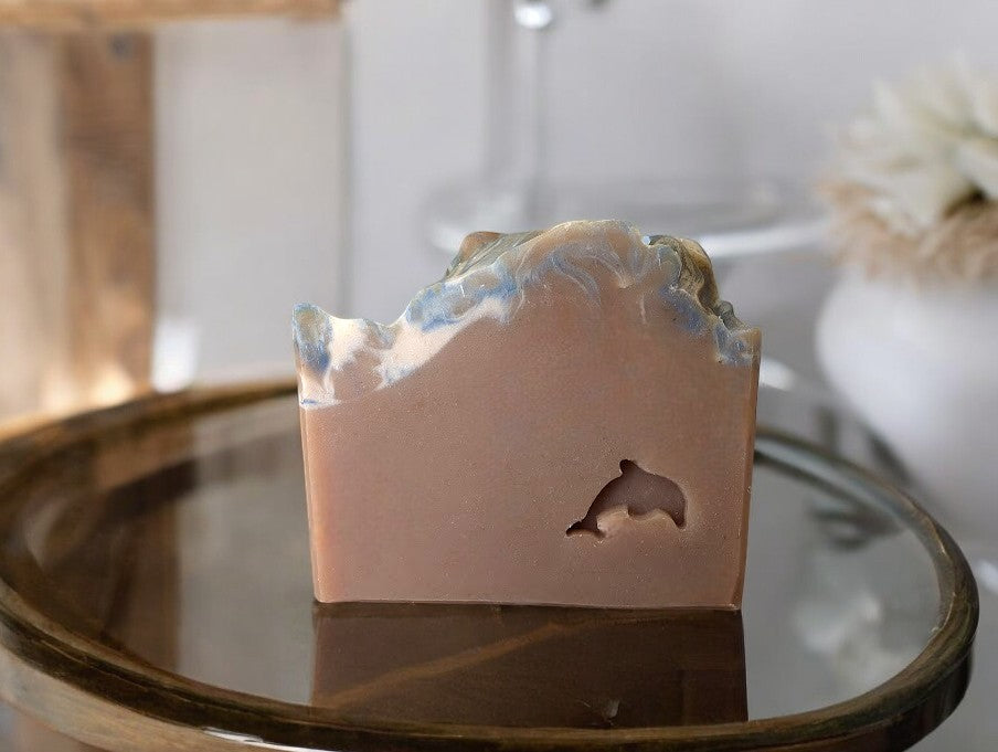 Handcrafted Goat Milk and Tallow soap with a woody gourmand scent. Topped with swirls of gold and blue on a solid tan base. Scent includes velvet plum, sugared violet, vanilla orchid, whipped amber, sheer sandalwood, and fresh vetiver. Reminiscent of a brazilian sunset glow, similar to Cheirosa Delicia Drench 59®. It’s divine and a perfect addition to your shower routine.