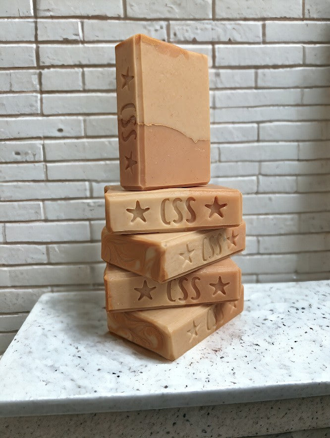 Handcrafted, cold process soap featuring tangerine and tan block coloring separated by a gold mica line.  The scent is a refreshing blend of tangy citrus fruits (lemon, lime, grapefruit) paired with subtle notes of cucumber, pineapple, blackberry, and champagne. Think Burst of Energy* and you'll understand the scent.