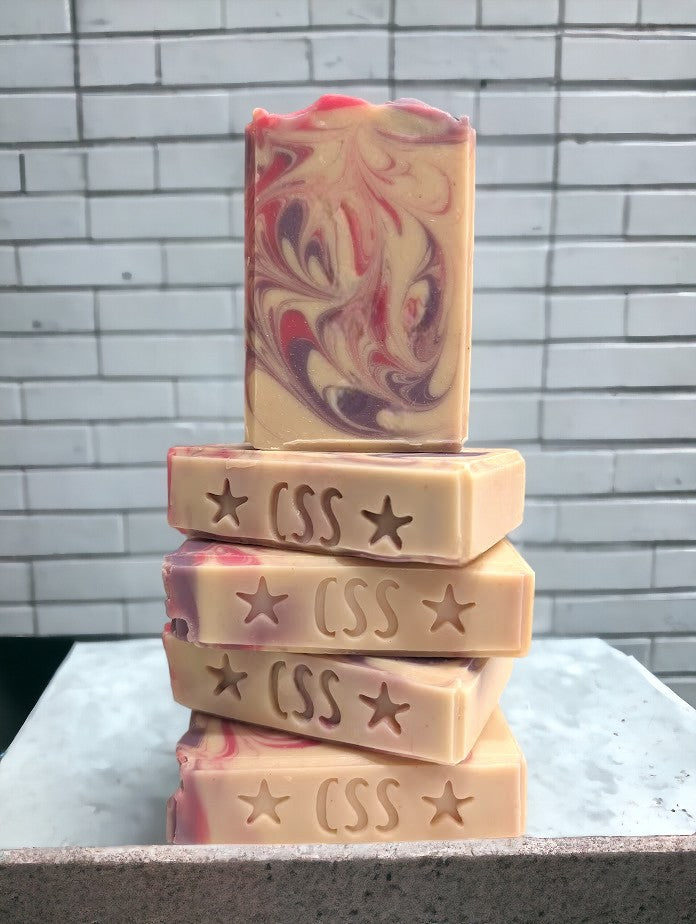 Creamy white handmade soap with delicate swirls of pink and purple. Top adorned with pink and purple swirls. Great for skin and your personal care routine. Featuring Coconut Milk, colloidal oats and kaolin clay. Available in 3 sizes: regular bar, small bar and Travel / Guest / Hotel sized bars.