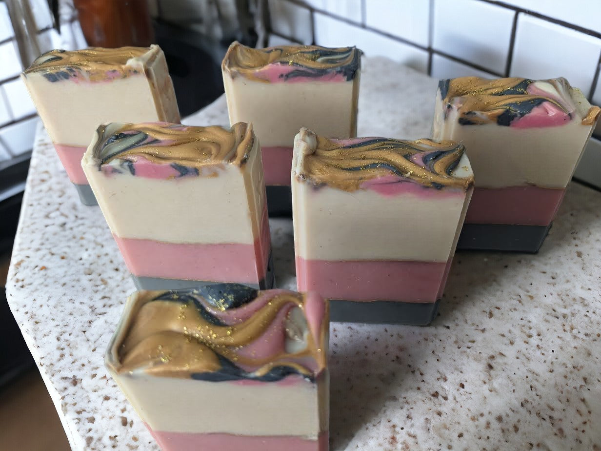 This beautiful handmade soap boasts Cocoa, Shea, Mango and Kokum butters and has layers of white, pink, and grey that are separated by elegant gold mica lines. Fragrance and essential oil blend (think Coco Mademoiselle*) will leave you feeling refreshed and rejuvenated.