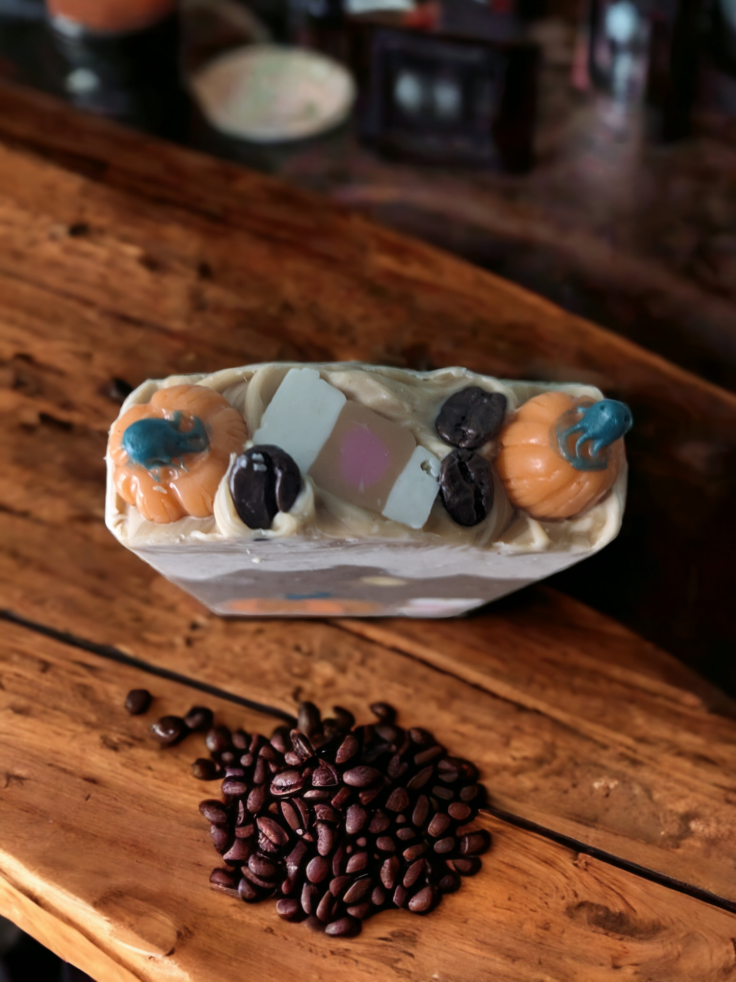 Pumpkin Spice Latte To Go, Luxury Artisan Bar soap . The top of the handcrafted soap bar has a creamy white top that is decorated with delightful pumpkins, a to go coffee cup and coffee beans. The body of the bar of soap has light latte brown with a pumkpin and to go coffee cup that go through the width of the soap.