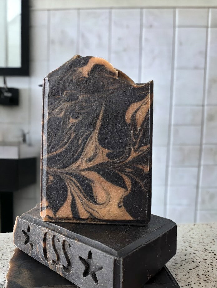 Black soap with gold swirls. Healthy and skin loving ingredients include Activated Charcoal, Kaolin Clay, Colloidal Oats and Coconut milk. Fragranced with Lavender and Black Amber Fragranced Bar Soap.