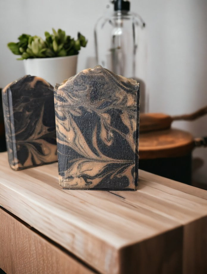 Small batch, handcrafted Black soap with gold swirls. Healthy and skin loving ingredients include Activated Charcoal, Kaolin Clay, Colloidal Oats and Coconut milk. Fragranced with Lavender and Black Amber Fragranced Bar Soap.