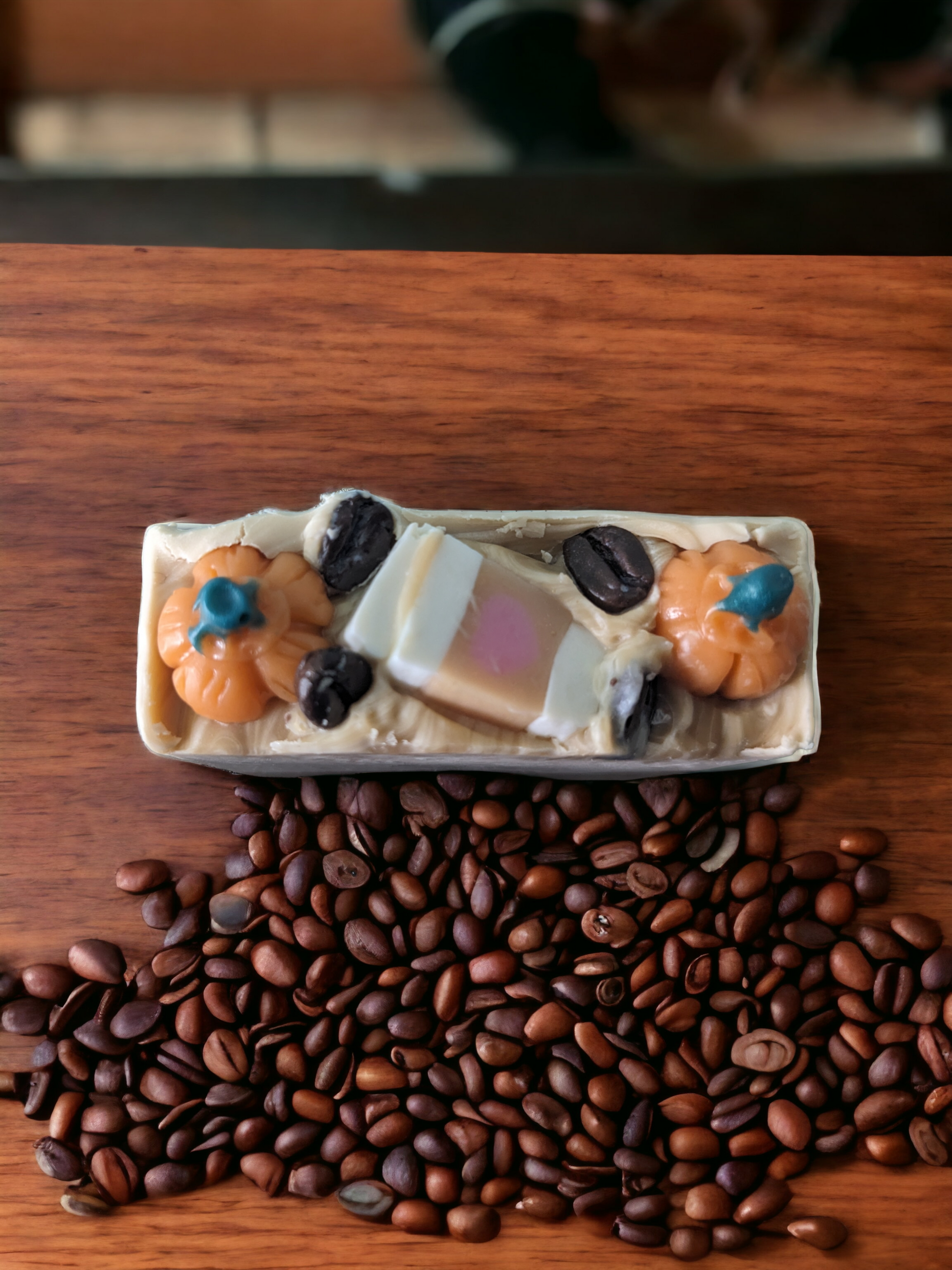 Pumpkin Spice Latte To Go,  Luxury Artisan Bar soap .  The top of the handcrafted soap bar has a creamy white top that is decorated with delightful pumpkins, a to go coffee cup and coffee beans.  The body of  the bar of soap has light latte brown with a pumkpin and to go coffee cup that go through the width of the soap.