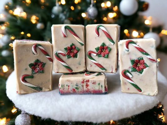 Handmade bar Soap decorated with Candy Canes and a poinsettia on top.  Body of the soap is layered starting with green, then red and a creamy white with red and green soap sprinkles and a little sparkle.