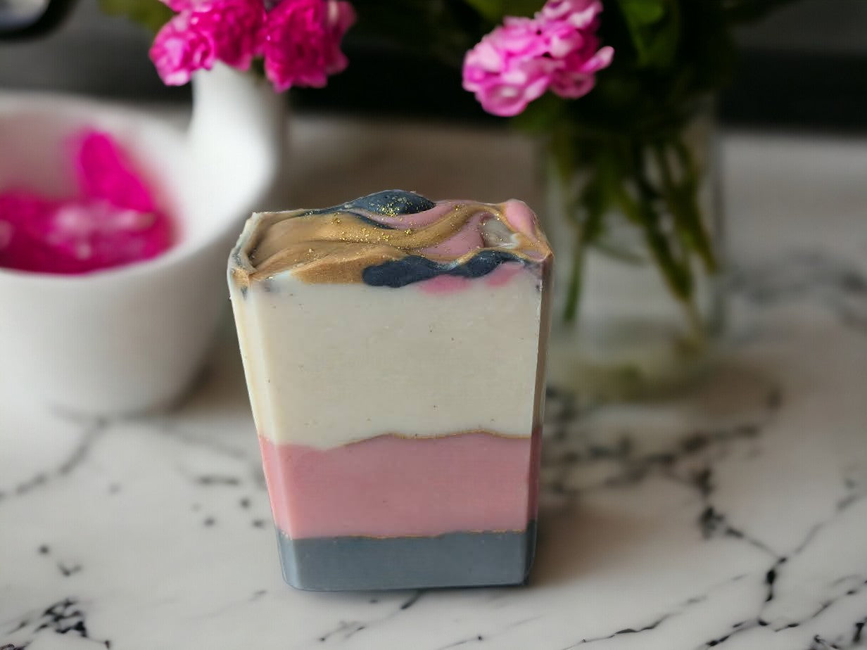 This simple artisan soapis anything but! Brimming with Cocoa, Shea, Mango and Kokum butters and other skin loving ingredients, it has layers of white, pink, and grey that are separated by elegant gold mica lines. Fragrance and essential oil blend (think Coco Mademoiselle*).  This soap will definitely up your personal care game or is the perfect gift for that special someone in your life.