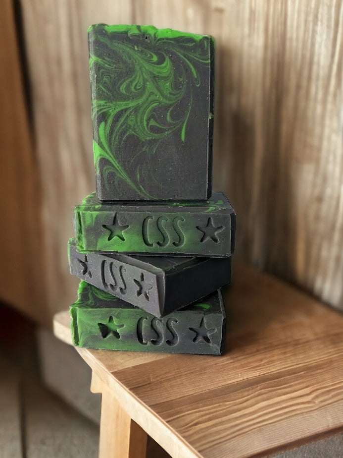 Handcrafted hemp oil and goat milk soap bar with black background with a dusting of holographic sparkles with delicate neon green swirls dancing throughout the soap body.  Topped with biodegradable star glitter.  Up your skin care game with Aurora-Hemp-ealis.  Fragranced with Agave Bloom fragrance oil.