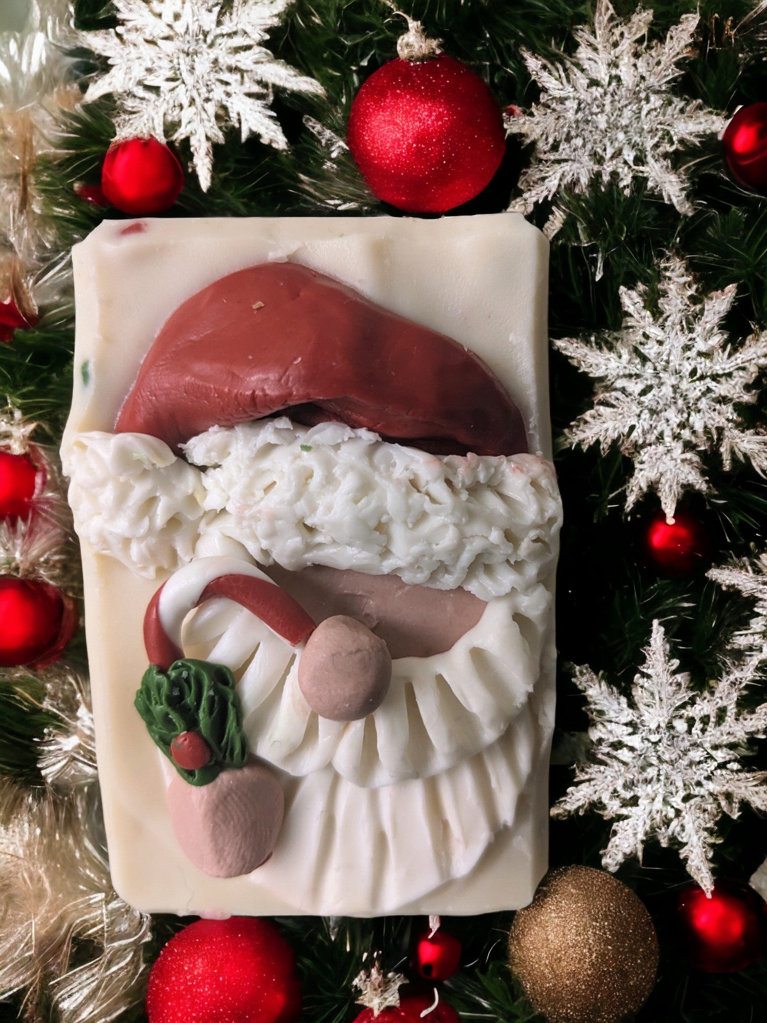 Handcrafted bar Soap with a Santa Claus head on top.  Santa is holding a candy cane.  Body of the soap is layered starting with red, then green and a creamy white with red and green soap sprinkles.