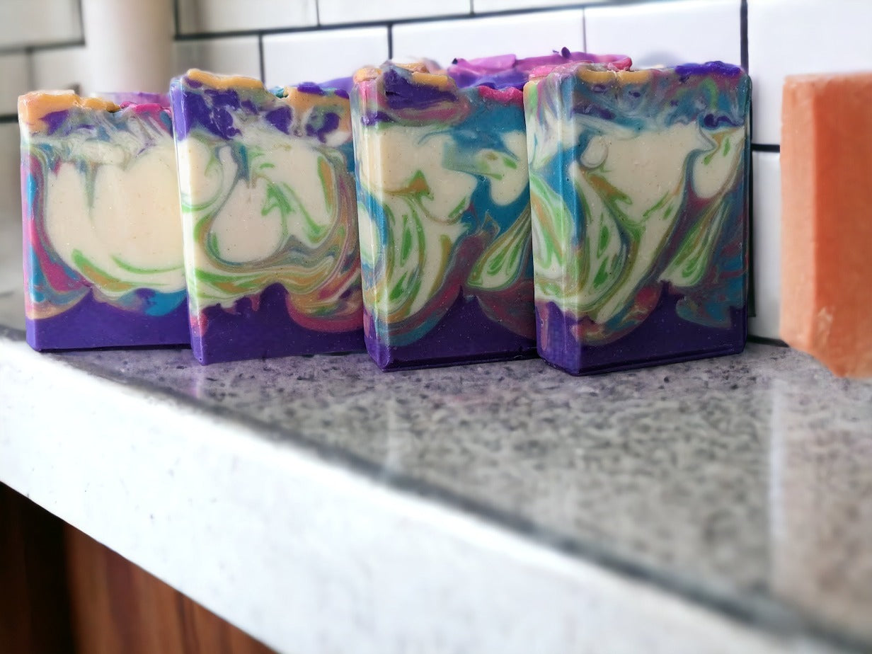 Delightful, decorative spring soap scented with midnight peonies.  Handcrafted Soap flowers in spring colors adorn the top of this luxury soap bar! Gentle swirls throughout the soap in the same color as the flowers in purple, pink orange, green and caribbean blue. Handmade in small batches with skin-loving Shea, Mango, Cocoa and Kokum butters, you'll feel as fresh as a spring morning! 