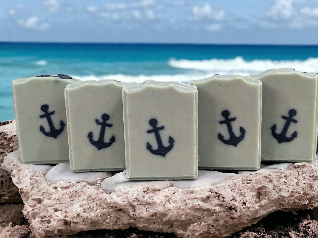 Simple tallow and goat milk soap featuring a navy blue anchor against a greenish-blue background.  Scented with 'Salty Mariner' the scent is a blend of a blend of lily of the valley, jasmine, leafy greens, pine, and musk, with a splash of fresh rain.