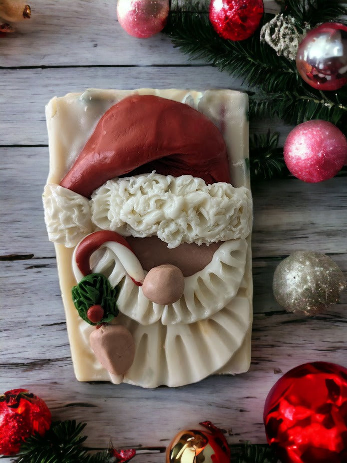 Handcrafted bar Soap with a Santa Claus head on top.  Santa is holding a candy cane.  Body of the soap is layered starting with red, then green and a creamy white with red and green soap sprinkles.